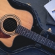 Acoustic guitar and notepad with pencil, top view.